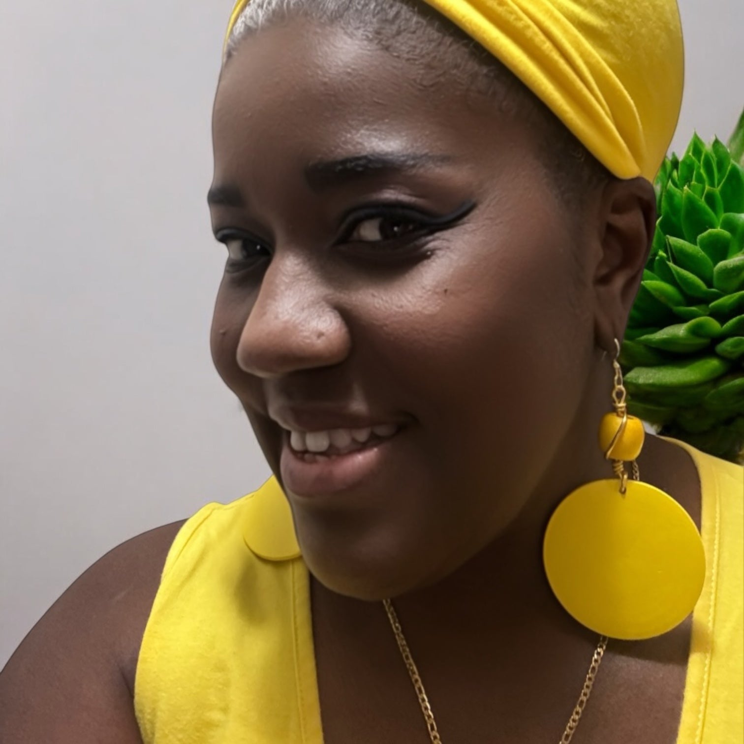 Model wearing vibrant yellow wood earrings with a matching ethnic headwrap