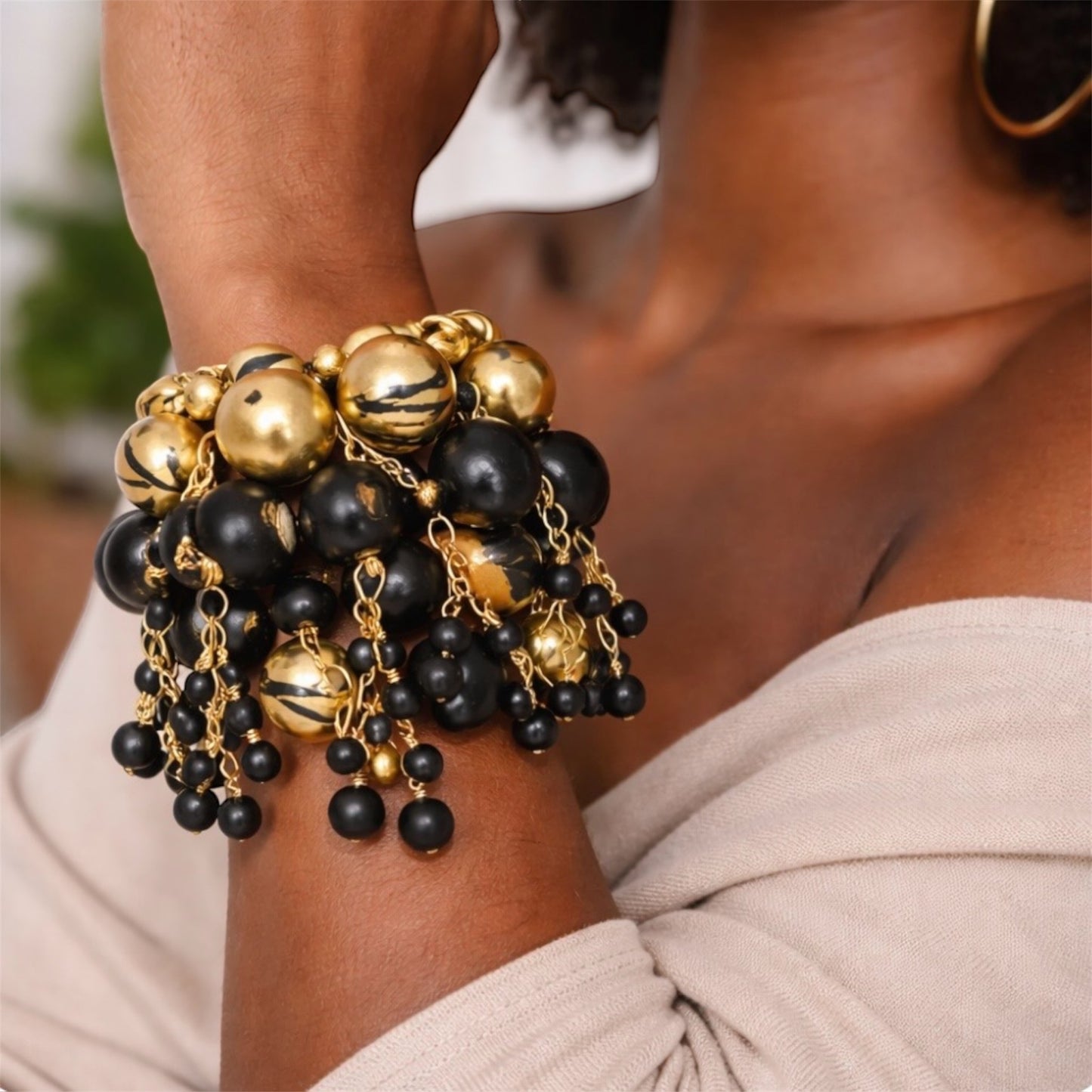 close-up of handmade Afrocentric gold and black wood bead bracelet stack with dangling charms