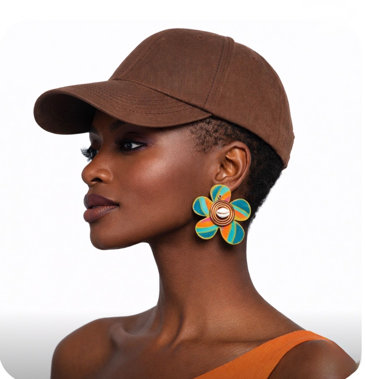 Side profile of a beautiful dark skin woman with very short natural hair wearing a brown cap and colorful Afrocentric cowrie shell statement earrings on a clean white background