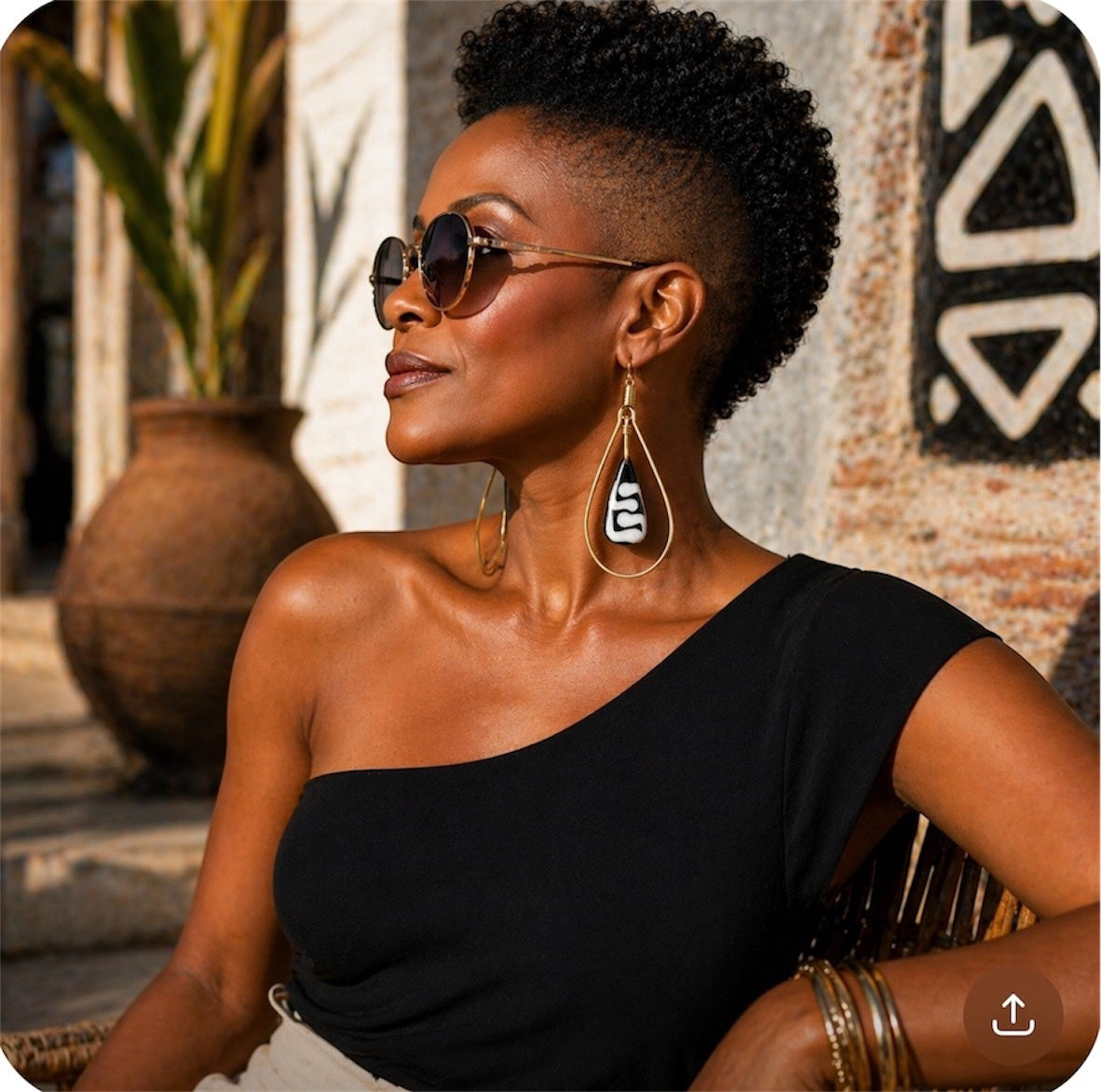 Afrocentric gold teardrop earrings with carved bone drop worn by stylish Black woman in outdoor lifestyle setting