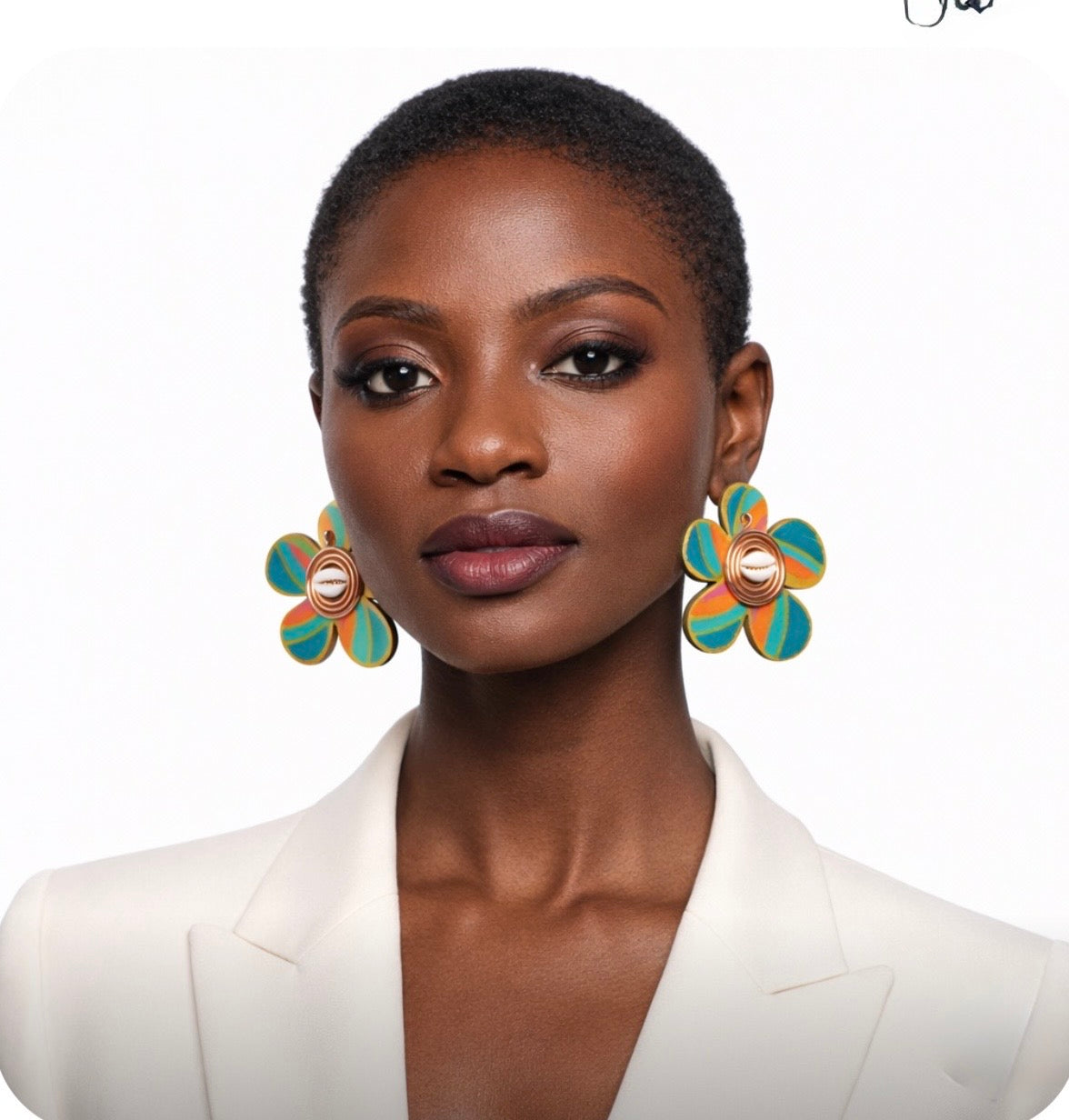 Alt Text:
Beautiful dark skin woman with very short natural hair wearing a cream suit and colorful Afrocentric cowrie shell statement earrings facing forward on a clean white background
