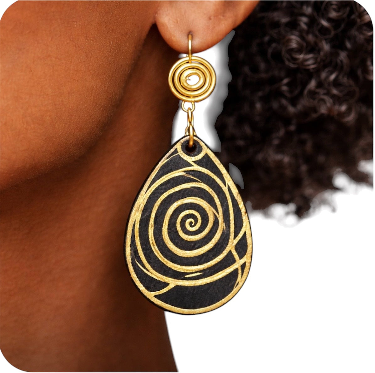 Close-up view of Afrocentric black and gold spiral wood statement earring worn by dark skin woman with grey afro on clean white background showing texture and detail