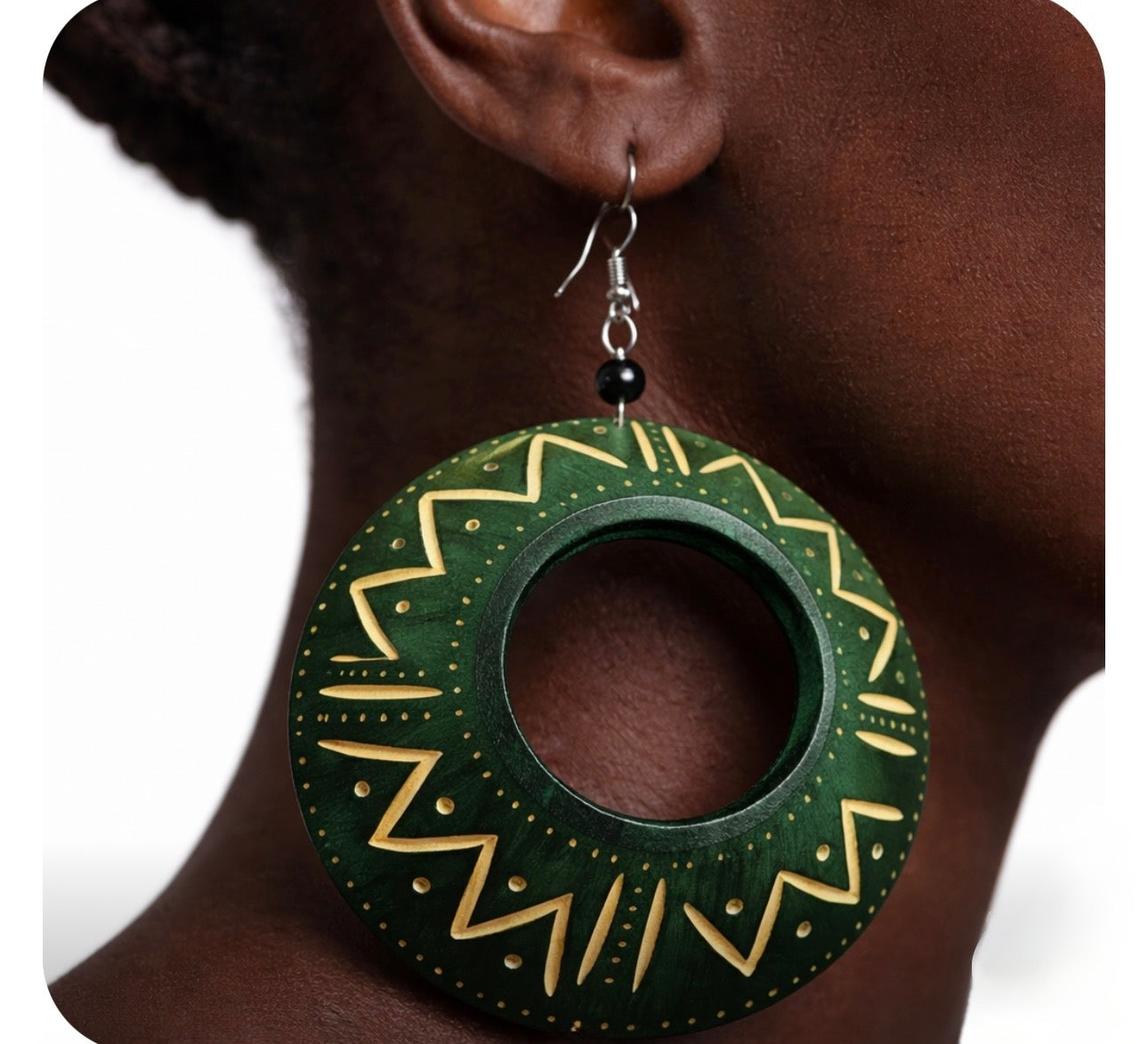 Close up of afrocentric green calabash statement earrings showing hand carved wood texture and gold tribal patterns on dark skin model handcrafted jewelry detail
