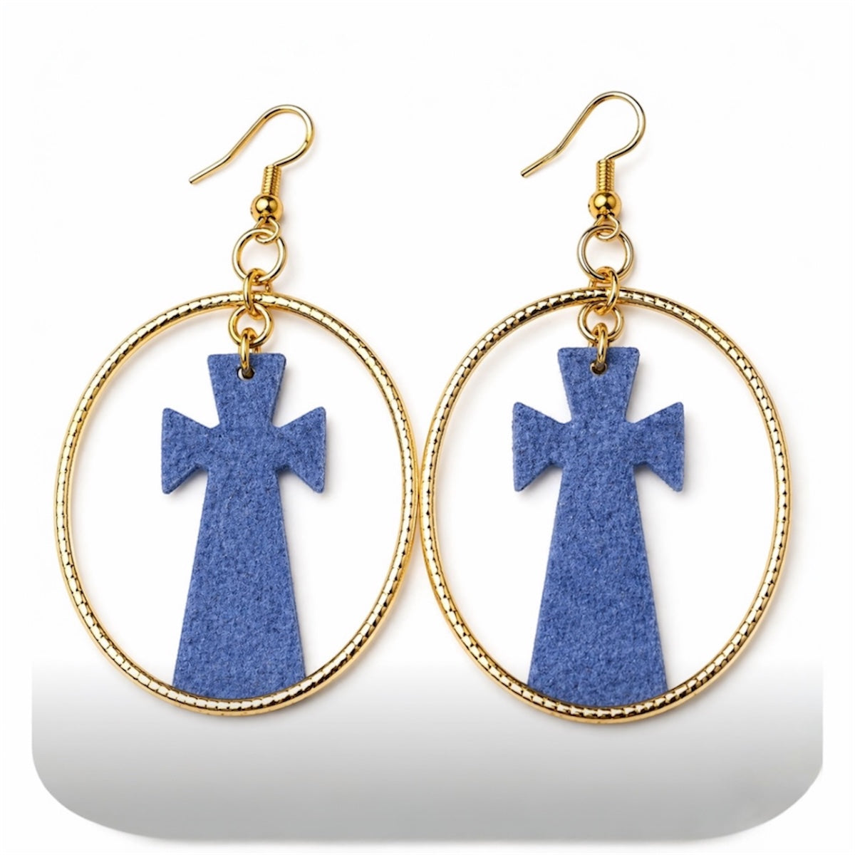 Close up of afrocentric grey cross hoop earrings on white background showing texture and gold hoop detail