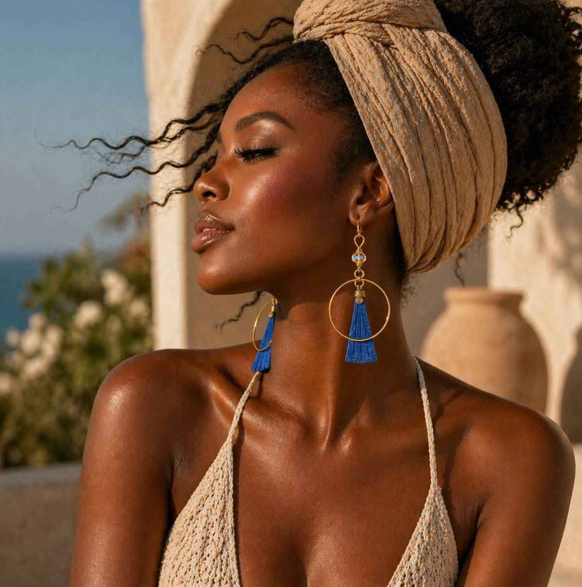 Side profile of a dark skin woman wearing Afrocentric blue bone and gold hoop earrings showing movement and length detail