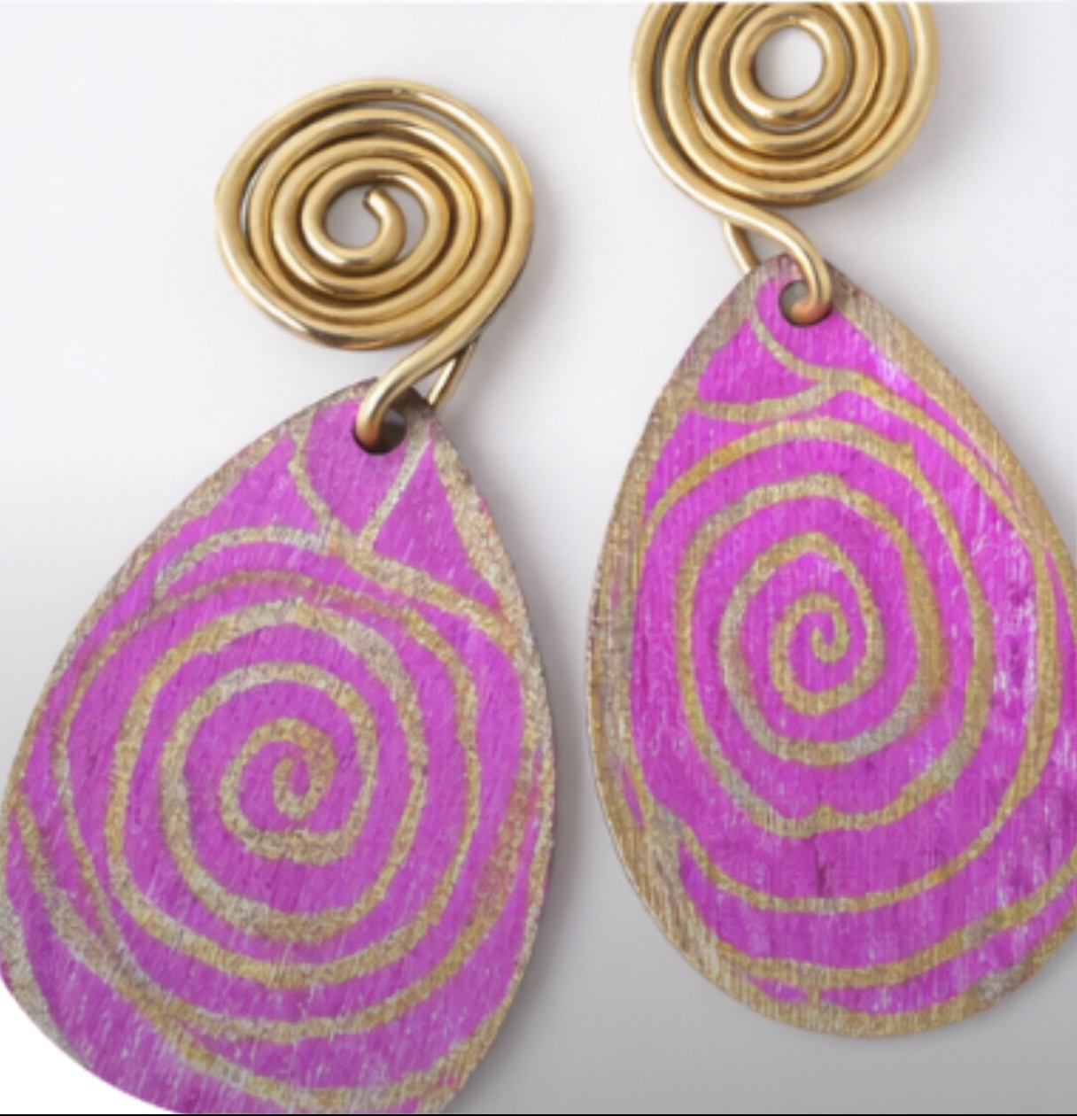 Close up of pink and gold spiral wooden earrings showing hand painted texture and gold detailing