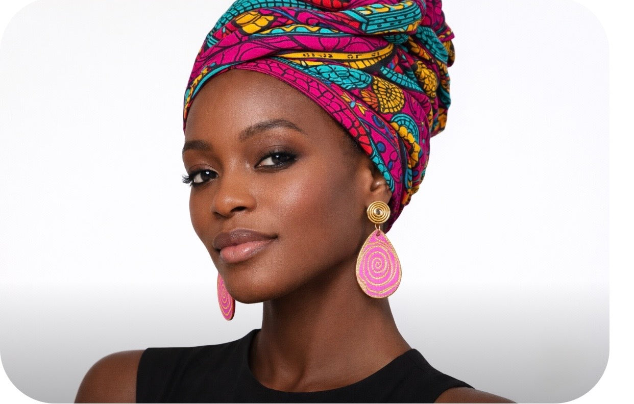 Dark skin woman wearing vibrant headwrap and pink gold afrocentric spiral earrings bold cultural jewelry