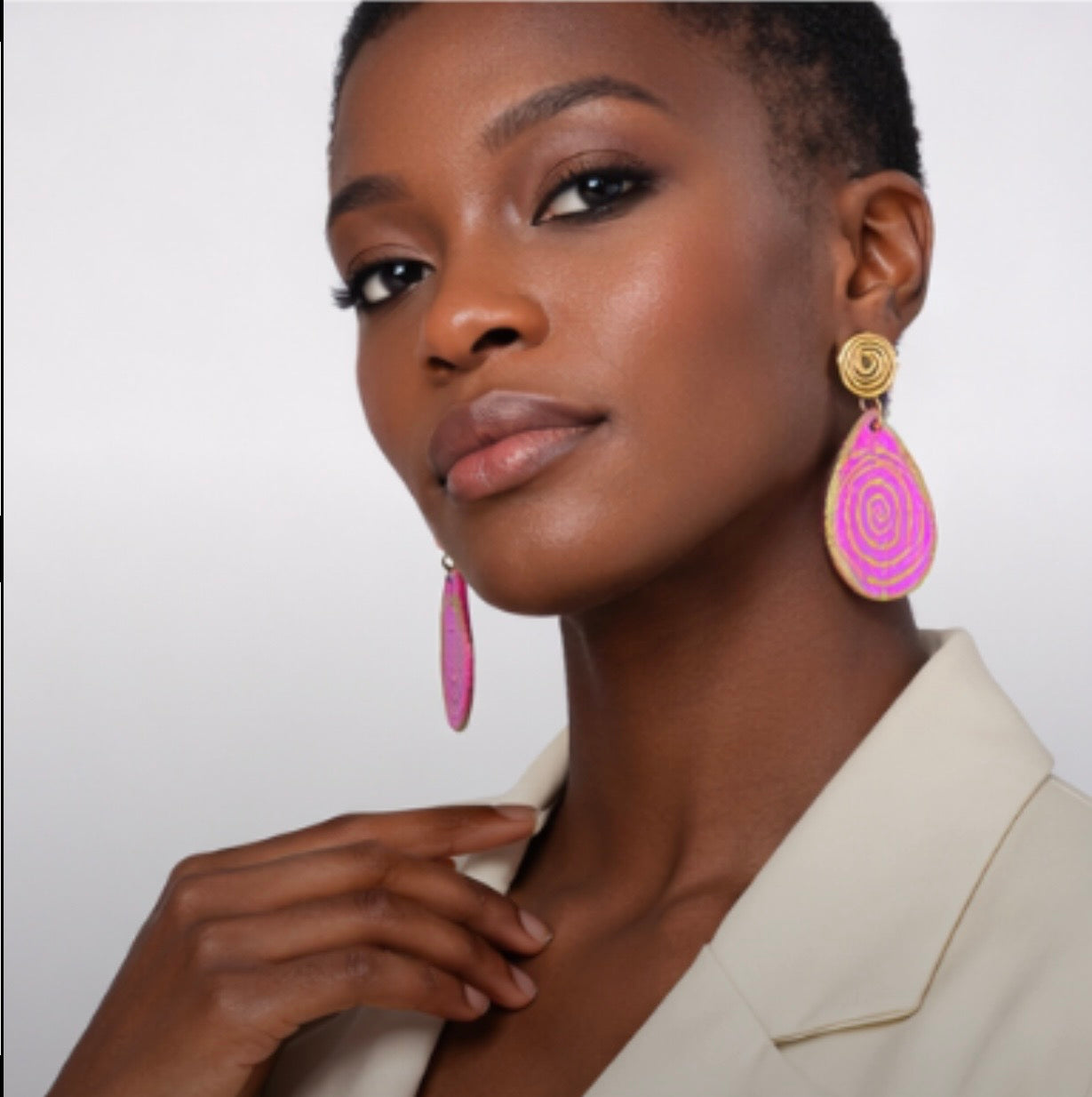 Stylish woman wearing pink and gold afrocentric statement earrings with outfit showing bold fashion styling