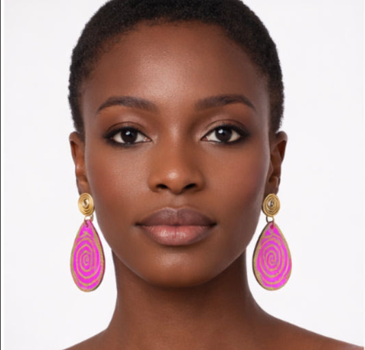 Dark skin woman with short hair wearing pink and gold afrocentric spiral statement earrings facing forward