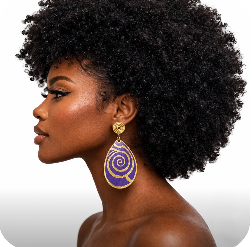 Side profile of dark skin woman with large kinky Afro wearing purple and gold Afrocentric statement earrings on clean white background