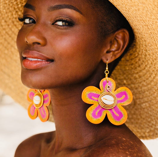 Dark skin woman wearing oversized Afrocentric Sunset Bloom Earrings with a large summer hat in a styled lifestyle image