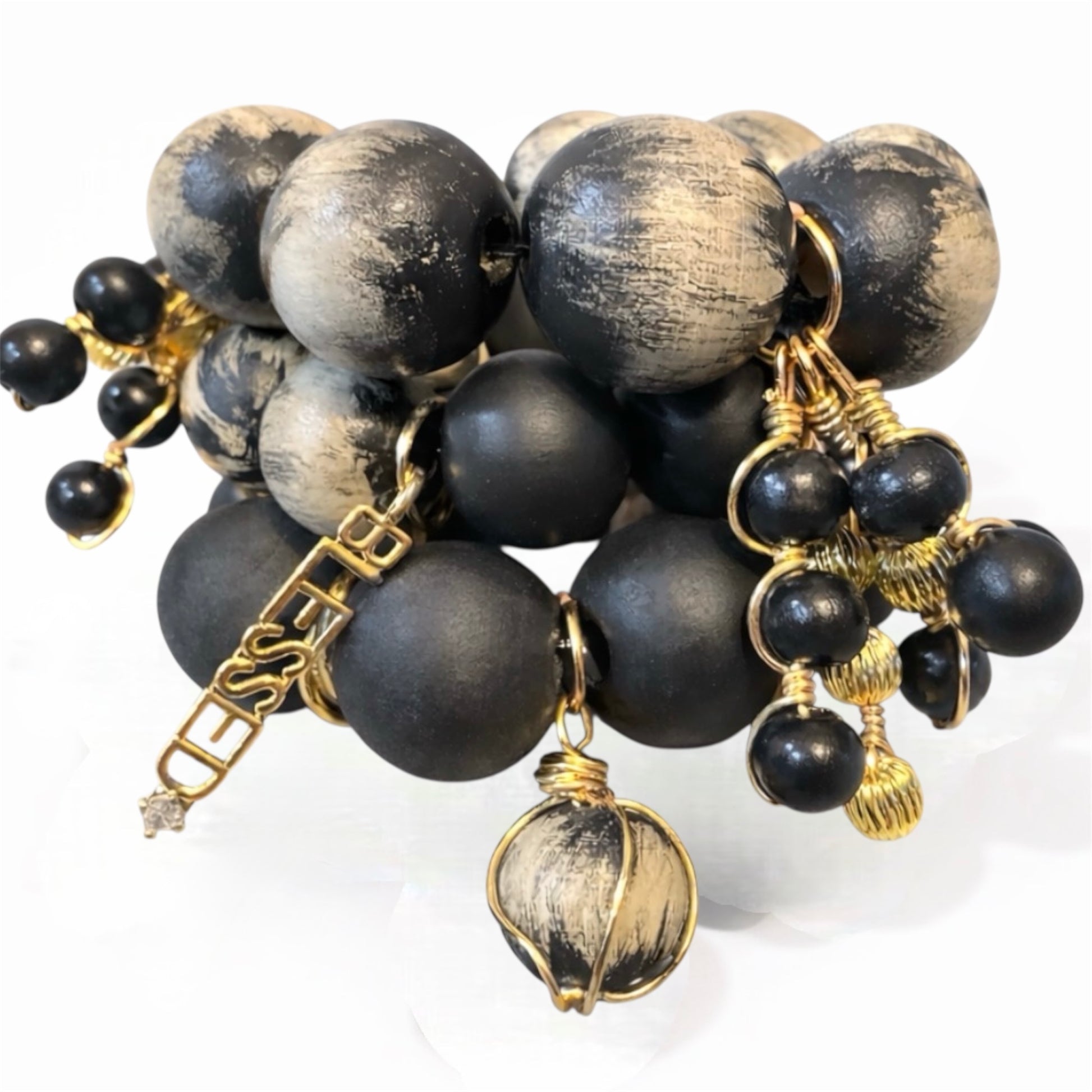 Handcrafted black and cream Afrocentric bracelet stack with 25mm painted beads, matte black beads and gold charms on white background