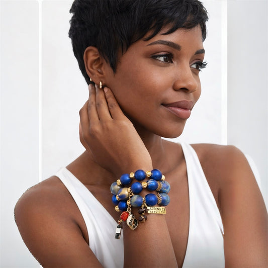 Brown skin woman with pixie cut wearing chunky blue and gold 25mm wood bead statement bracelet trio with strong is beautiful charm