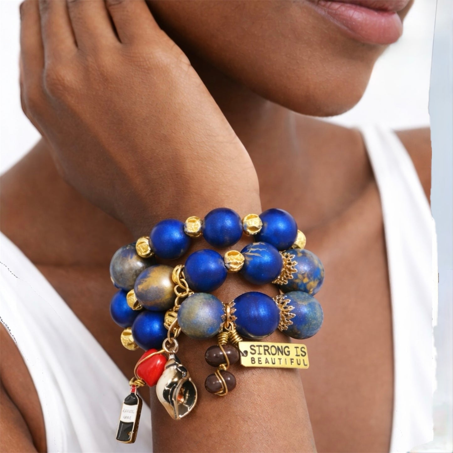 Close-up of chunky 25mm hand-painted wood bead bracelet stack in blue and gold on brown skin model showcasing bold Afrocentric statement jewelry
