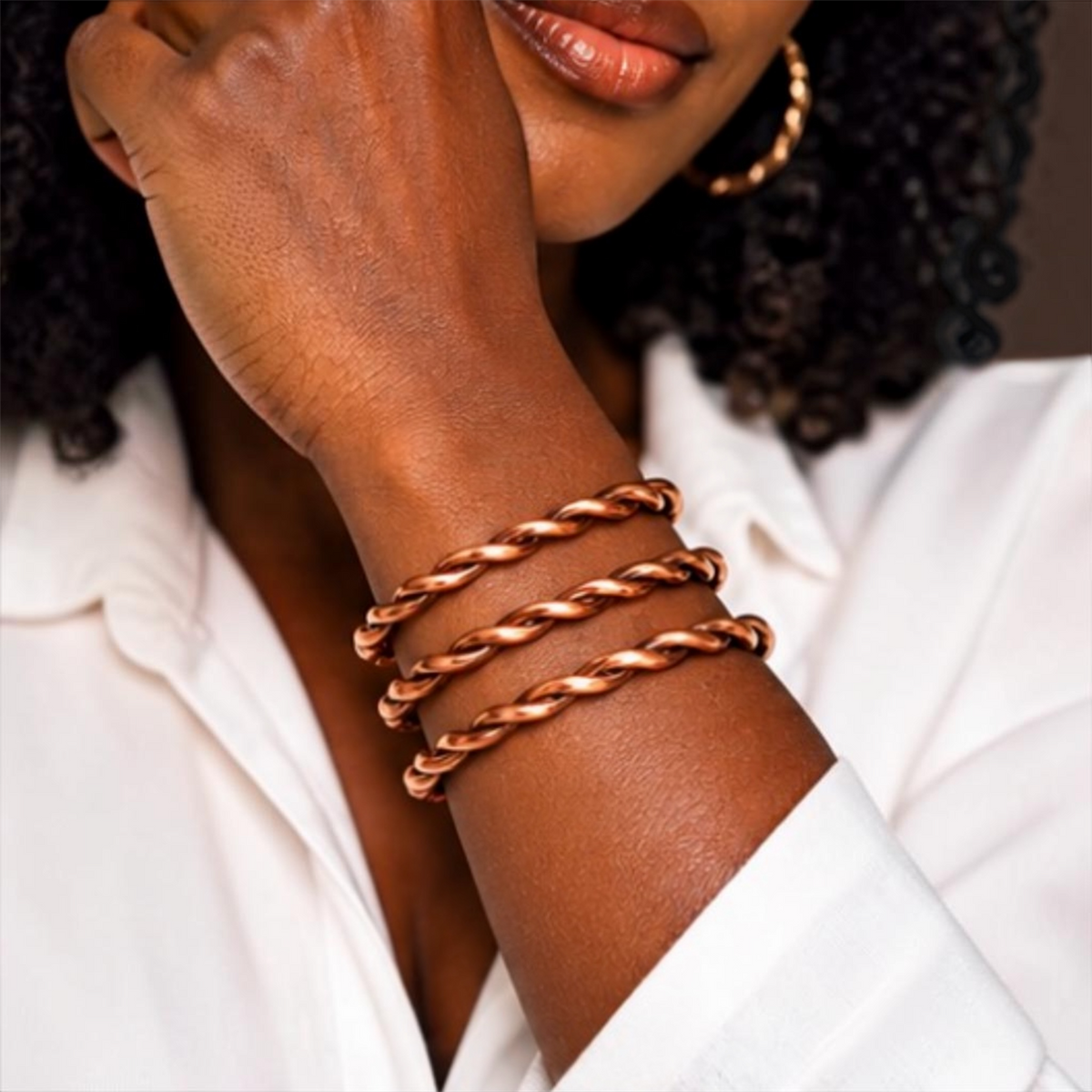 Black woman wearing three handmade adjustable pure copper twisted bracelets stacked on wrist