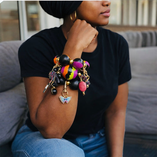 Brown skin woman wearing chunky Afrocentric bracelet stack with black headwrap and black t-shirt