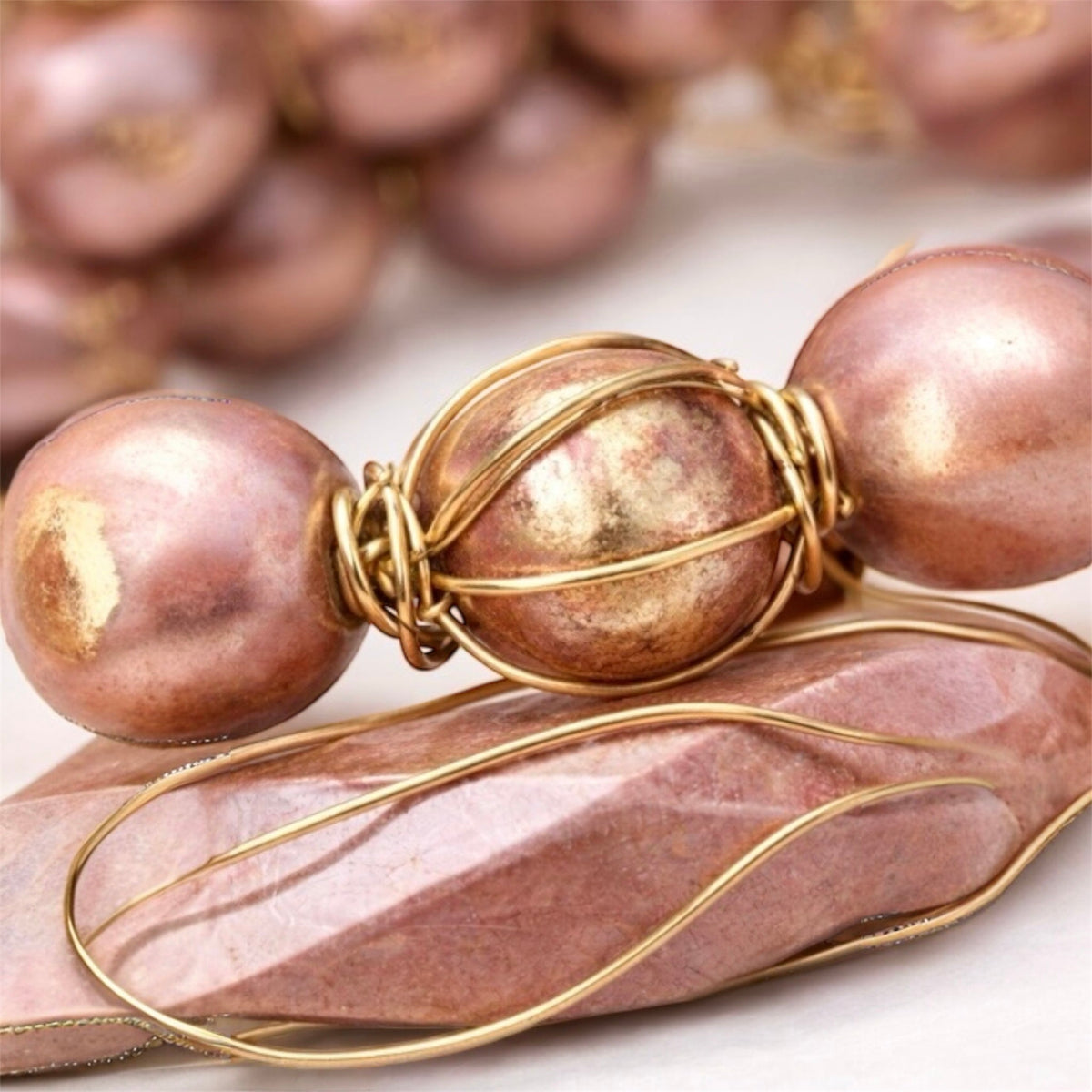 Woman wearing blush and gold Afrocentric bracelet stack with round and oblong gold wire wrapped focal beads